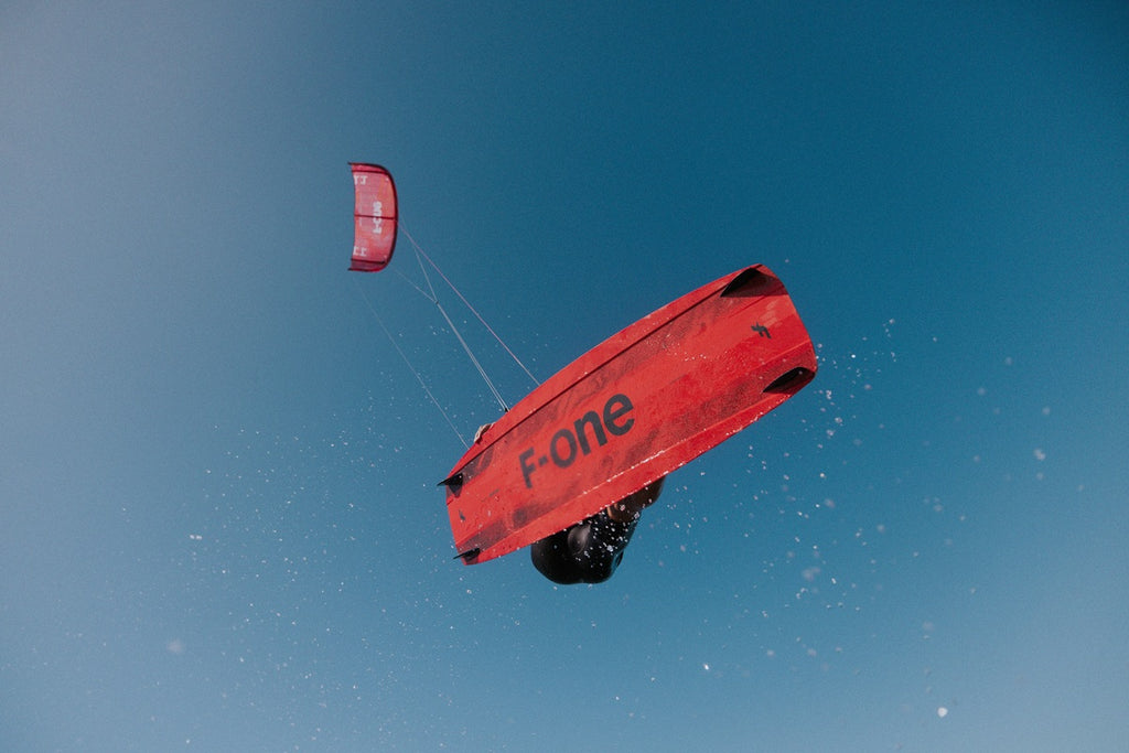 Kiter springt mit F-ONE Spark Hybrid während man das Board von der Unterseite sieht